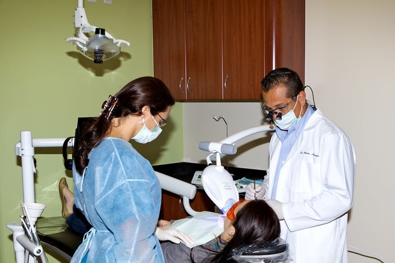 A patient during a dental procedure with the doctor and a female assistant