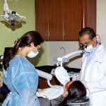 A patient during a dental procedure with the doctor and a female assistant